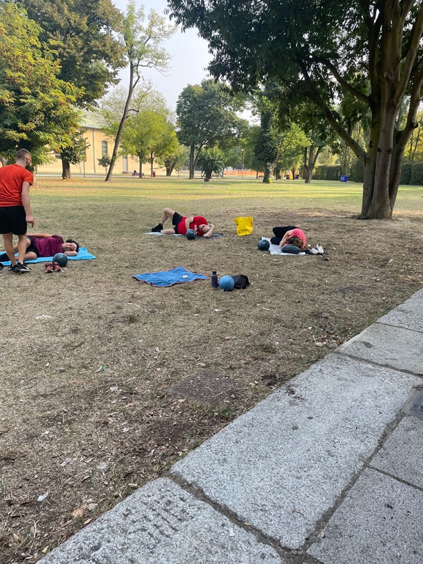 L'istruttore ed alcuni partecipanti mentre eseguono alcuni esercizi a terra al parco.